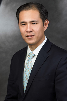 Headshot of Richard Lee, who smiles while wearing a black suit and a teal tie