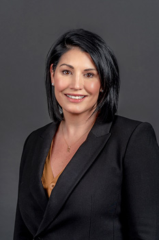 Headshot of Robyn Misiano, who smiles while wearing a burnt orange blouse and black blazer suit