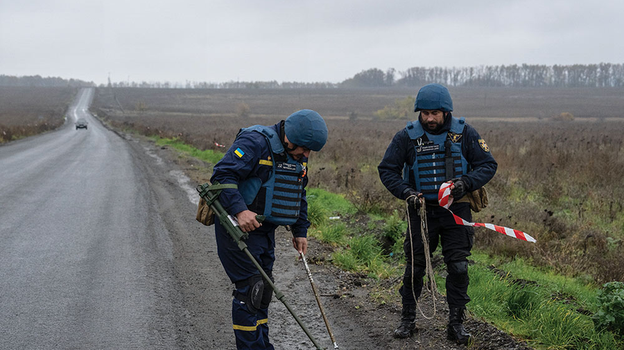 Members of a mine clearance team search a roadside for mines and improvised explosive devices