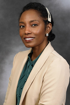 Headshot of Sarah Mcqueen, who smiles while wearing a green blouse and tan blazer