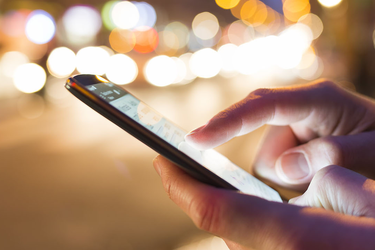 Close up photo of a persons hands interacting with their smart phone. 
