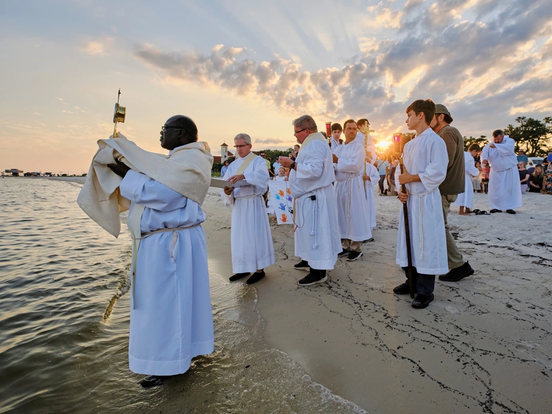 Father Vincent Ajayi, parochial vicar of St. Thomas the Apostle Catholic Church in Long Beach, Miss., lifts the monstrance over the Gulf of Mexico during a &ldquo;Blessing of the Sea&rdquo; held June 12 as part of the Juan Diego Route of the National Eucharistic Pilgrimage. (Photo by Dan Anderson)