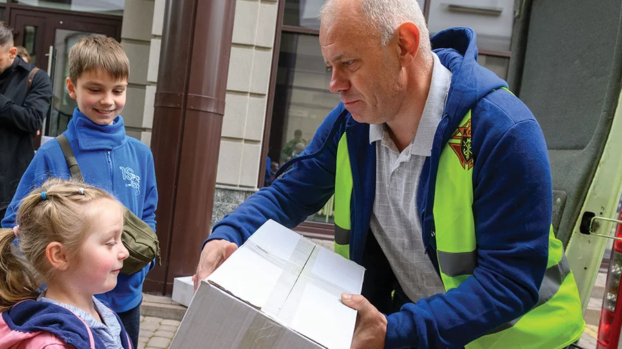 Myroslav Mazur, a member of Andrey Sheptytsky Council 15804 in Ivano-Frankivsk, Ukraine, hands a care package to a girl