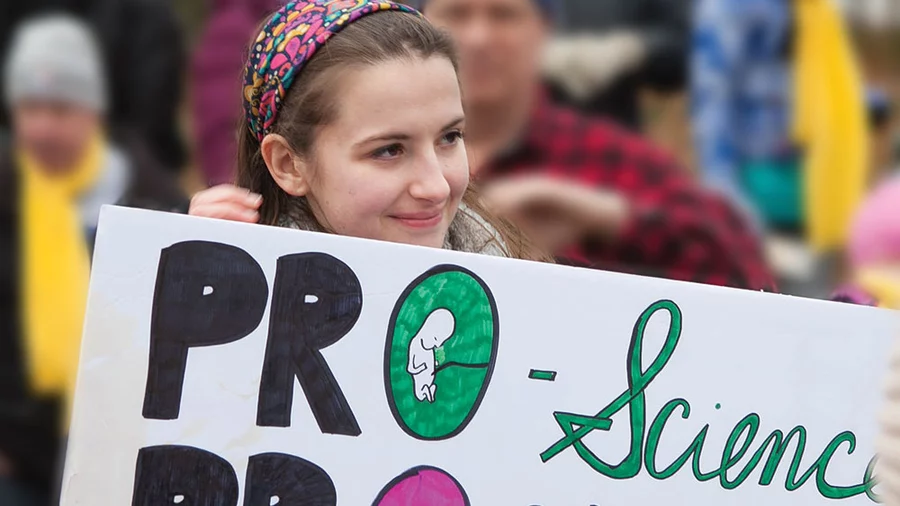 Girl stands outside at the March for life holding a sign