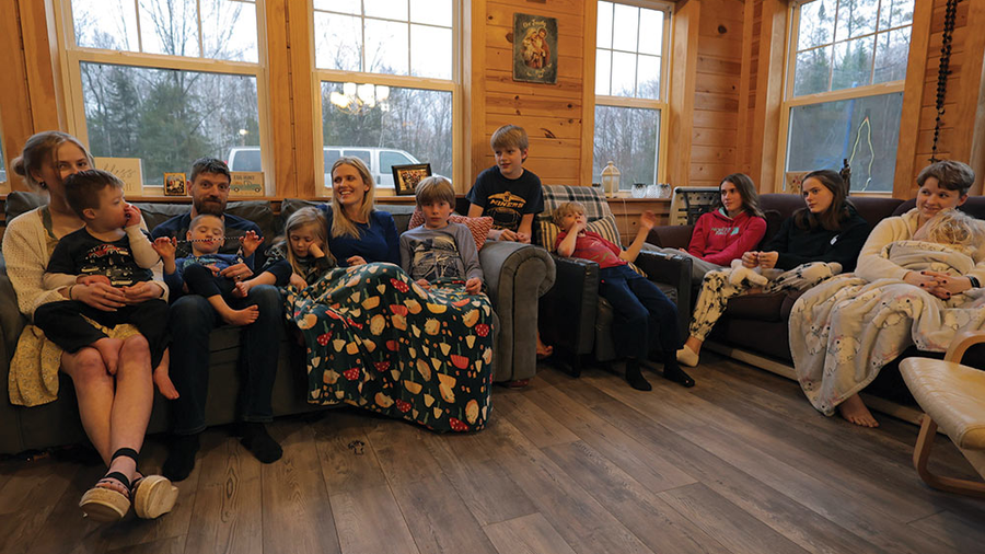 A family sitting on a couch at home praying together