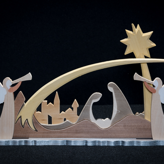 Carved wood nativity scene that includes the Holy Family beneath a star with a city silhouette in the background. Two angels complete the scene.