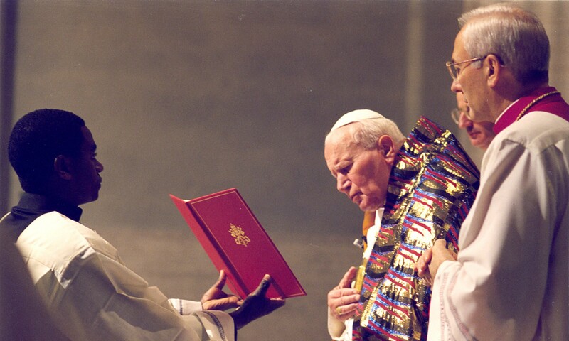 Le pape au Vatican, debout avec deux autres personnes, célébrant la messe de minuit.