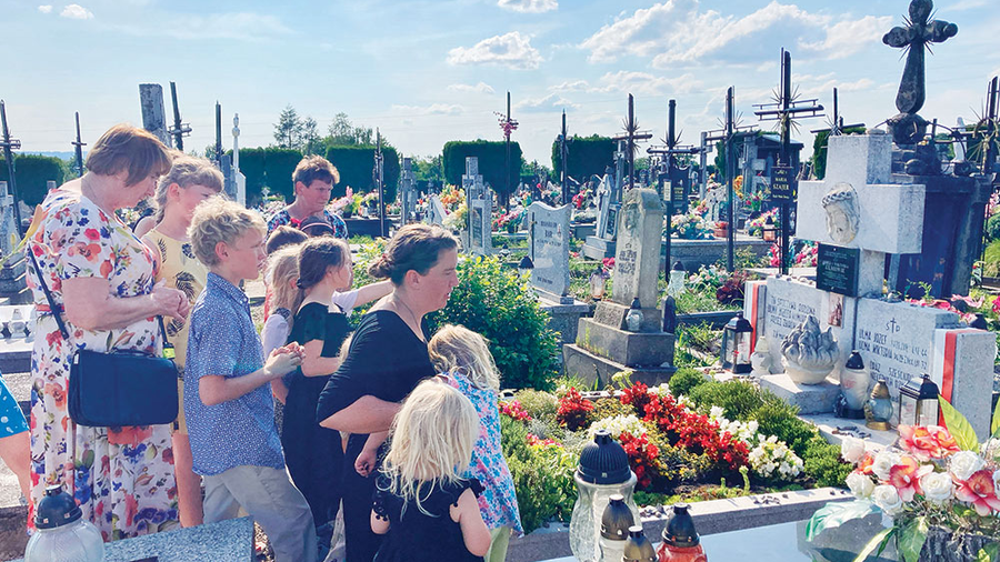 Kelly Lindquist and her children pray at the grave site of the Ulma family.